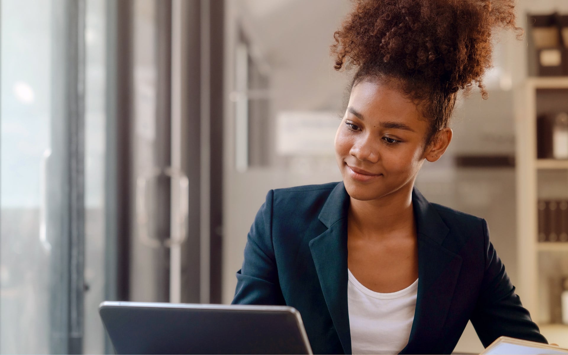 Eine Frau im Büro am Schreibtisch die auf ein Laptop vor sich schaut