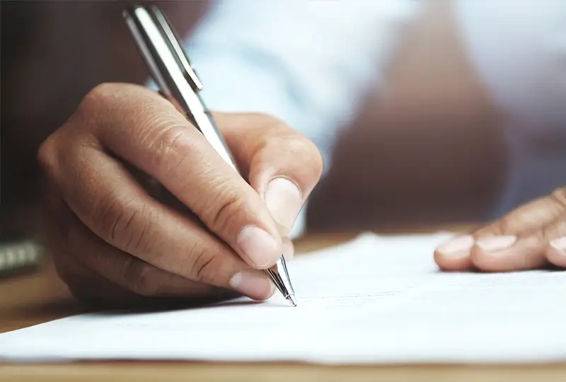 Mann, der mit einem Stift auf Papier schreibt